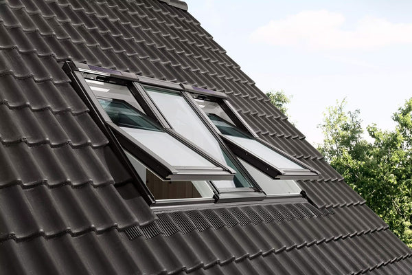 Twee geopende VELUX dakramen op zonne-energie op een schuin pannendak, met zichtbaar zonnepaneel bovenaan elk raam