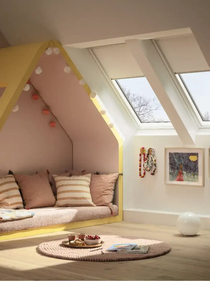 Attic kids room with sloped ceiling and VELUX roof windows, cozy reading nook.