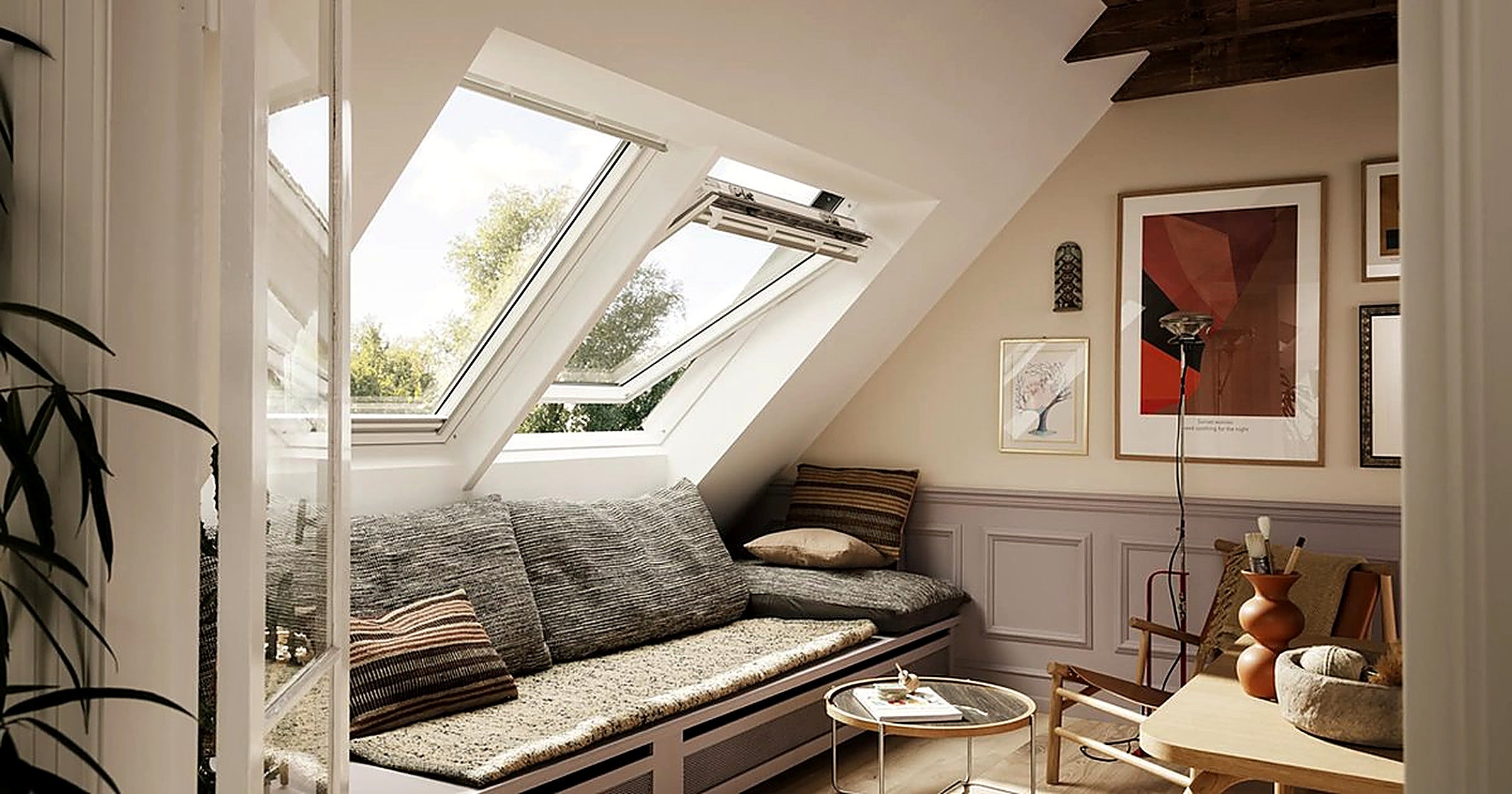 Warme zolderwoonkamer met openslaand Velux-dakraam, bank en kunst aan de wand